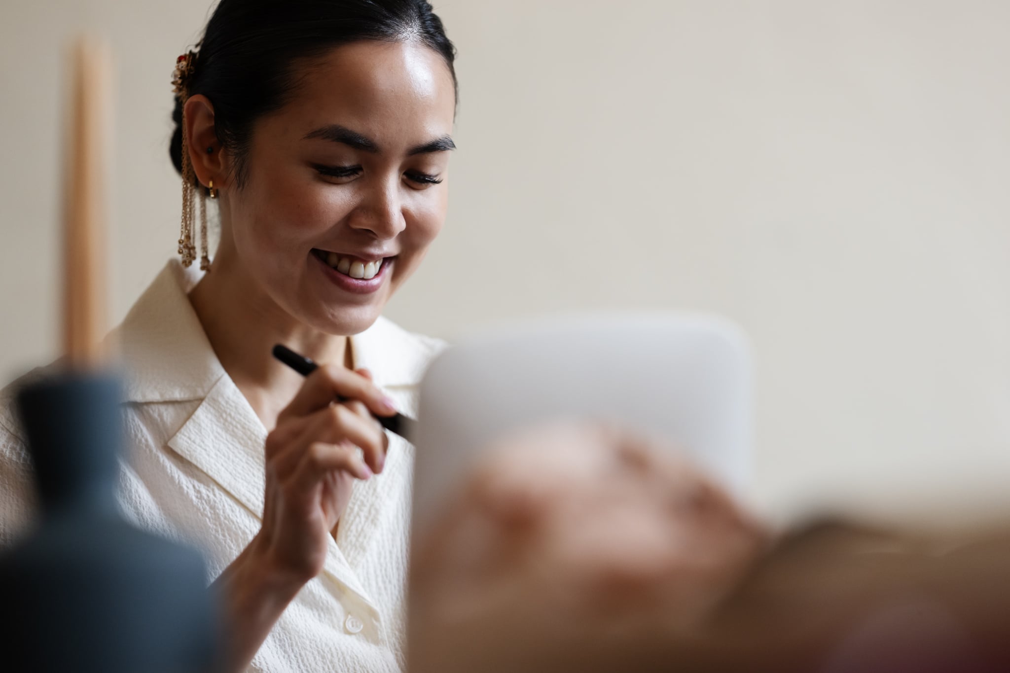A woman in a white blouse smiles while using a stylus on a digital tablet, perhaps planning her dream London wedding at No. 4 Hamilton Place.