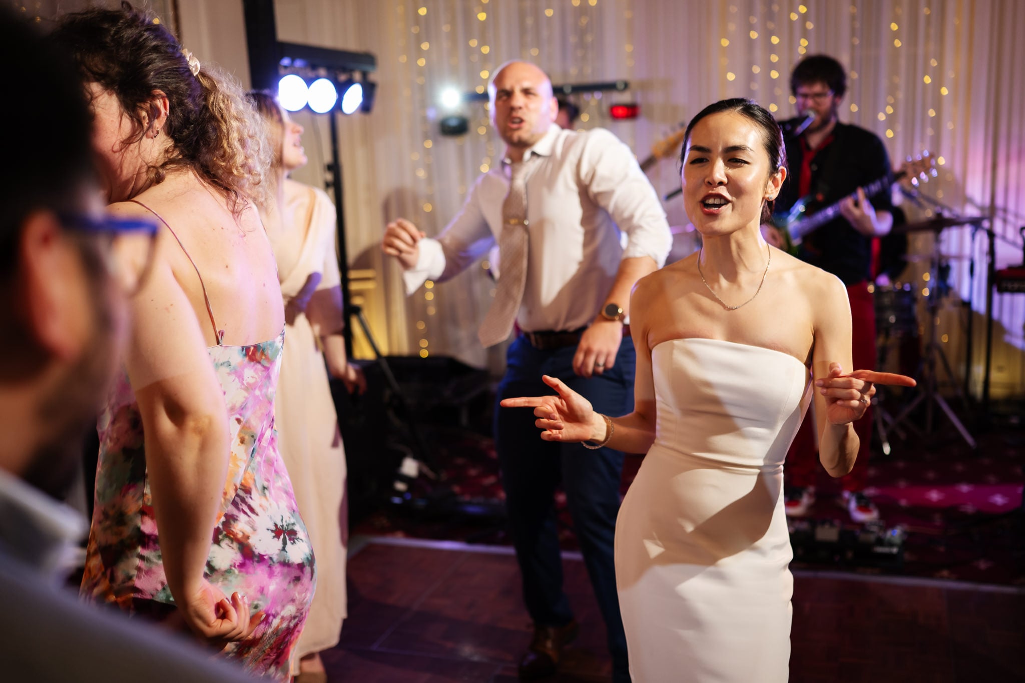 People in formal attire dance and enjoy live music at an elegant indoor event at No. 4 Hamilton Place, with string lights and a band setting the scene for a memorable London wedding celebration.