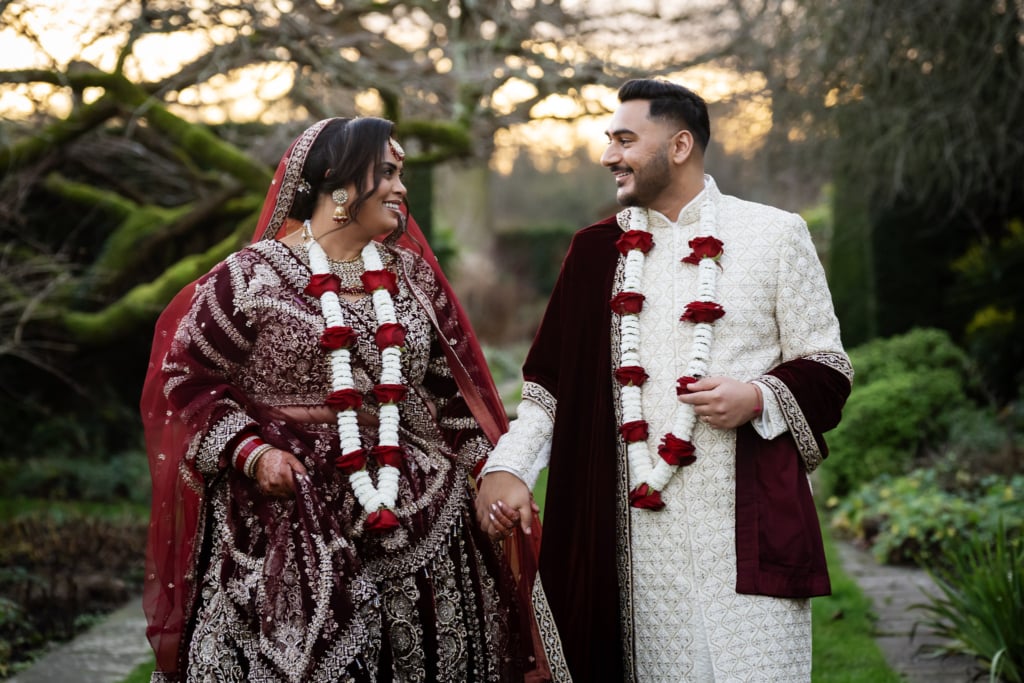 A walking portrait of the bride and groom at their Hindu wedding at Micklefield Hall