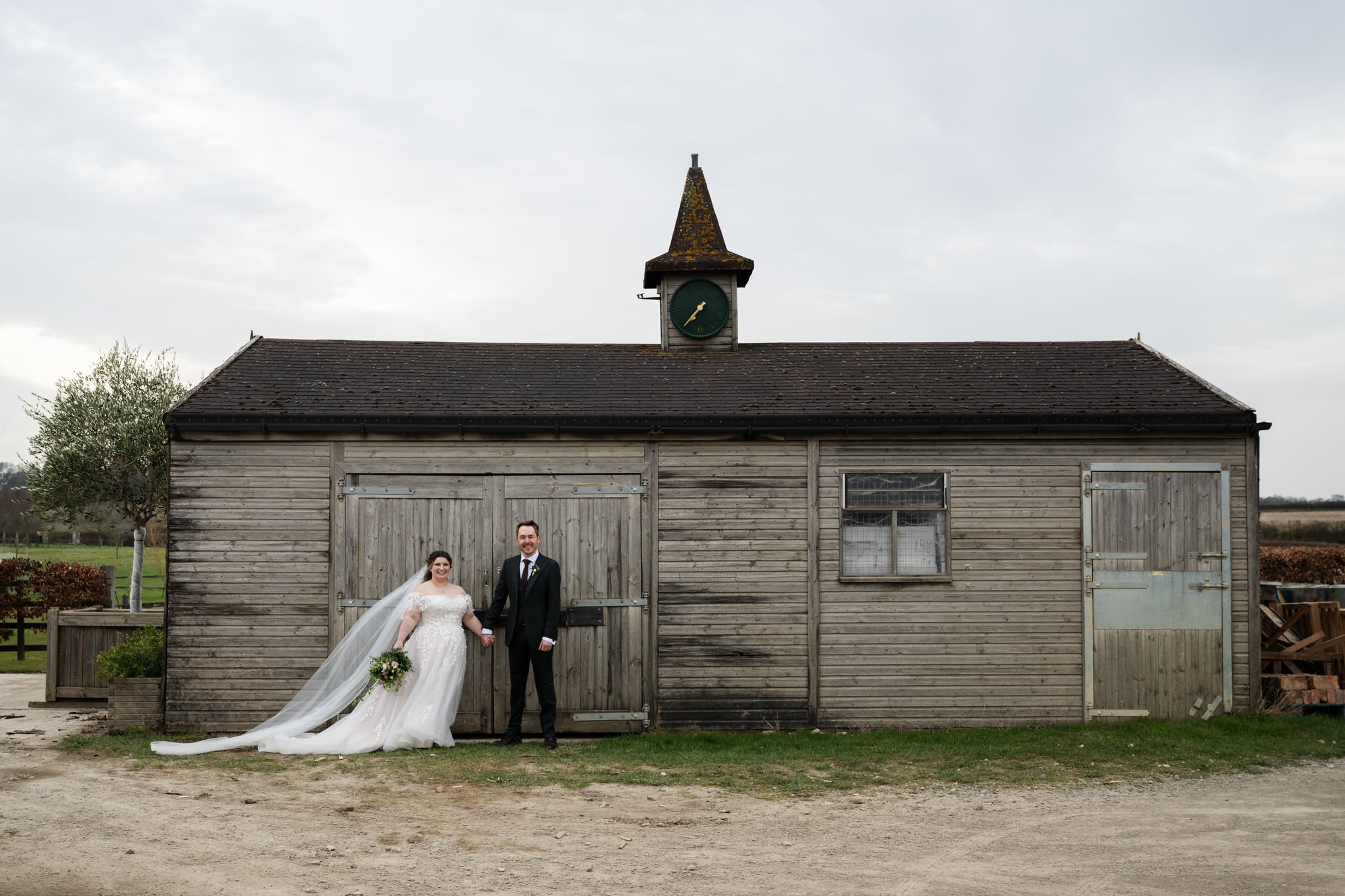 A bride and groom holding hands in front of the barn